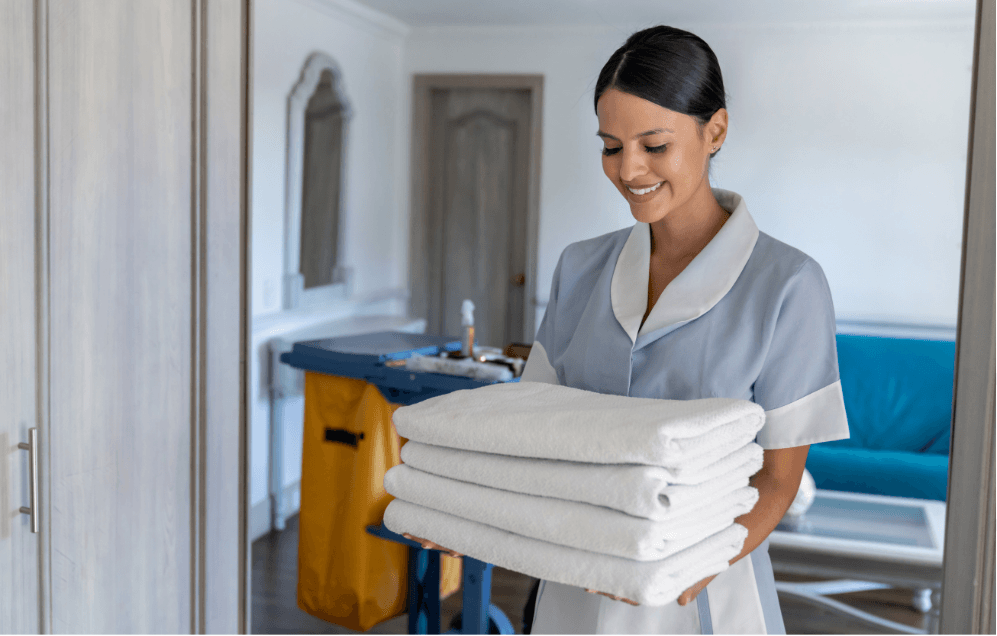 Hausdame mit Handtüchern neben dem Reinigungswagen im Hotelzimmer