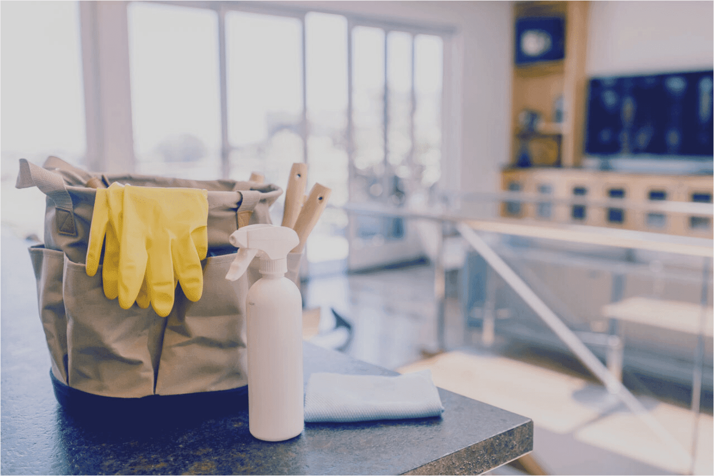 Reinigungstasche mit Handschuhen und Sprühflasche in einem hellen Büro