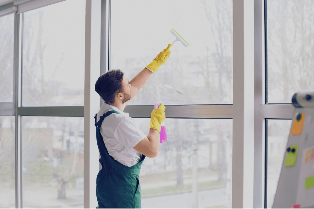 Glasreinigung: Reinigungskraft säubert eine große Fensterfront